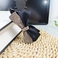 Detail einer schwarzen Haarklammer mit Schleife und goldenen Strasssteinen auf Matte - Champagner Strass