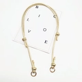 Close-up of golden braided shoulder strap featuring metallic rings and knotted details - Gold Ring Buckle / Gold