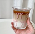 Primer plano de taza de vidrio con lazo rosa y bebida de café y leche en capas - 330ML / Taza Corta Acampanada con Lazo Rosa