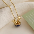Macro detail of golden bunny pendant in blue eggshell on minimalist box chain - Royal Blue