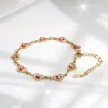 Detail of gold heart link bracelet with red evil eye charms and star flare effect - Red Eye