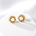 Dettaglio degli orecchini a torsione dorati con perla centrale e zirconi colorati - Oro