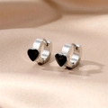 Macro shot of silver stainless steel hoop earrings with black enamel heart details on satin - Heart Hoop