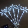 Detail showing five LED snowflake garden stake lights with solar control box on dark wood - White Snowflake-1 to 5 (Waterproof Battery)