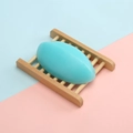 Blue oval handmade soap on a minimalist natural wood soap holder over a pastel background - 110g Thai-style Mint Soap