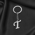 Polished stainless steel keychain with letter T pendant on black silk surface - Letter T