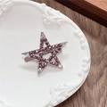 Detailed view of Y2K star-shaped hair clip with pink rhinestones on a white plate - Hollow Star / Purple