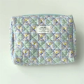 Detailed view of blue floral quilted cotton makeup bag with zip closure and fabric label - Green Plaid Floral