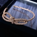 Dettaglio del fiocco di strass scintillanti su un cerchietto di lusso in metallo dorato - Fascia Sottile Annodata con Strass Champagne Completi