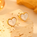 Luxurious gold heart earrings with white pearl inlay displayed on a stone surface - Pearl Heart Stud Earrings G304