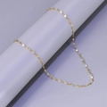 Close-up of golden stainless steel melon seed chain draped on a gray pedestal - L22-Lip Chain / Gold