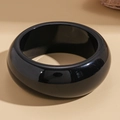 Dettaglio di un bracciale largo in resina nera con una finitura a specchio lucidata - Stile Minimalista Nero Lucido