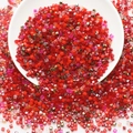 Macro view of red and gold square glass beads scattered in a white ceramic bowl for DIY craft - Red Series