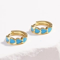 Detail shot of golden hoop earrings featuring blue enamel heart charms on a white surface - Heart-shaped Blue
