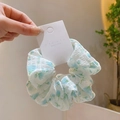 Chouchou rétro avec motif floral bleu sur tissu blanc présenté sur carte support - Chouchou à Petites Fleurs Vertes