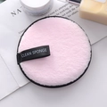 Pink round microfiber makeup remover pad with black ribbon handle on a white book - Light Pink
