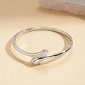 Macro detail van verzilverde open armband met witte edelsteen op beige stenen ondergrond - Zilver