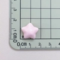 Macro shot of a 1cm pink resin star accessory on a green measurement cutting mat - Pink