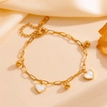 Gouden paperclip ketting armband met witte hartjes hangers en kralen op zijden achtergrond - Hart Goud Armband