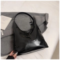 Primer plano de bolso de hombro en cuero charol negro sobre fondo de tela suave - Negro