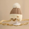 Close-up of thick cable knit texture and faux fur pompom on baby winter earflap hat - One Size (6 Months-2 Years) / Coffee/Off-white