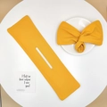 Detail of yellow fabric hair bun maker tool and printed bow accessory on a clean table - Yellow