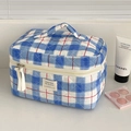 Detailed close-up of blue and white quilted toiletry bag with red line and dual zippers - Makeup Bag