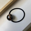 Close-up of minimalist hair tie featuring a dark brown cat-eye resin ball and black elastic - Black & Gold