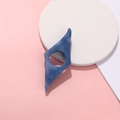 Macro detail of a blue resin thumb book page holder on a minimalist geometric pink background - Medium Blue & White