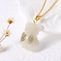 Gros plan d'un pendentif ours blanc texture sucre avec un nœud en strass sur chaîne dorée - Blanc