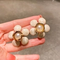 Close-up of camellia flower earrings with large faux pearls and golden metal edges - White