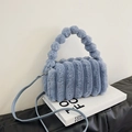 Blue fuzzy plush handbag with striped texture and furry ball handle on Tom Ford book - Blue