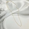 Détail d'un collier chaîne fine en argent S925 doré sur un plateau blanc décoratif - Chaîne à Maillons Dorée (45CM)