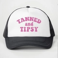 Detail van roze TANNED and TIPSY tekst op wit voorpand en zwarte mesh trucker pet - Eén maat / Zwart & Wit