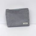 Detail view of grey corduroy makeup bag with mint green zipper and branded label - Gray