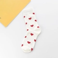 Flach liegende weiße Crew-Socken aus Baumwolle mit roten Herzmustern auf weißem Tisch - Einheitsgröße / Weiß