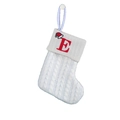 Close-up of white knitted Christmas stocking featuring red embroidered letter E and hat - Letter E