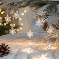 Warm white snowflake LED string lights hanging on snowy pine branches for Xmas decor - Snowflake