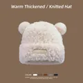 Detailed view of plush beige winter hat with cute bear ears and premium leather logo tag - White