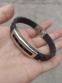 Detalle de pulsera de silicona negra con textura de escamas y placa de metal plateada - Patrón de Acero Cuadriculado