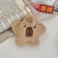 Close-up of star-shaped Capybara plush pendant with embroidery and lucky tag on book - Capybara Style