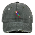 Close-up of vibrant parrot embroidery on distressed dark grey washed cotton baseball cap - Green