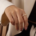 Elegant gold-tone open ring featuring a row of oval cubic zirconia on a female finger - Style B White