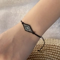 Detail eines verstellbaren böhmischen Perlenarmbands mit Rautenmuster am Handgelenk - Schwarz