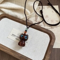 Macro shot of wooden cat pendant necklace with bright blue eyes on braided rope - Brown