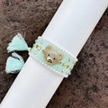 Macro view of hand-woven mint green bracelet with crystal bear charm and pearl trim - Mint Green