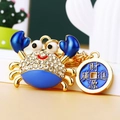 Sparkling crab keychain with blue enamel, crystals, and lucky charm in gold finish - Blue Lucky Crab with Coin