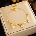 Detalle de una pulsera dorada con colgantes de corazón de circonita rosa en estuche - Rosa