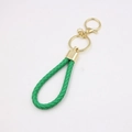 Détail d'un porte-clés en cuir tressé vert avec anneau doré et fermoir mousqueton pivotant - Vert