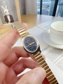 Close-up of golden metal watch with black oval dial and quartz movement detail - Gold Band Black Dial